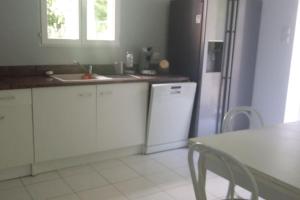kuchnia z białymi szafkami, lodówką i stołem w obiekcie CHARMANTE MAISON PAISIBLE 6 PERSONNES w mieście Vendays-Montalivet