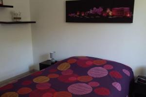 um quarto com uma cama roxa com um cobertor de bolinhas em CHARMANTE MAISON PAISIBLE 6 PERSONNES em Vendays-Montalivet