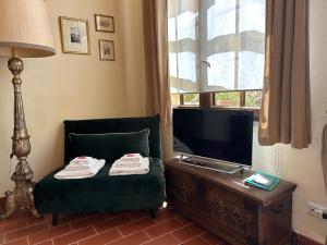 ein Wohnzimmer mit einem grünen Stuhl und einem TV in der Unterkunft La Limonaia Firenze in Florenz