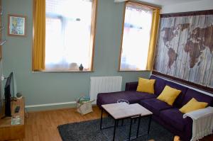 ein Wohnzimmer mit einem lila Sofa und gelben Kissen in der Unterkunft Citadelle Vauban, T2 l'encyclopédie in Lille