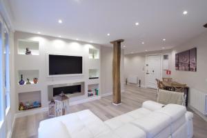 sala de estar con sofá blanco y TV en Habitaciones Turísticas Bilbao Centro con aire acondicionado, en Bilbao