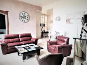 a living room with leather furniture and a clock on the wall at La Rose des Vents Le Vigan - Hyper centre - Parking in Albi
