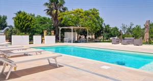 a swimming pool with two lounge chairs and a table at Villa Marzoni con Piscina Privata by HDSalento in Tiggiano