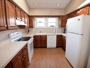 a kitchen with a white refrigerator and wooden cabinets at Surf Club Oceanfront Hotel in Dewey Beach