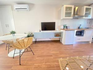 uma sala de estar com uma cozinha e uma mesa com uma televisão em Setubal Beach Vibes - Pátio em Setúbal