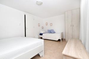 een witte slaapkamer met 2 bedden en een tafel bij V.A.G.I.A. Apartment in Vaia