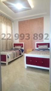 - 2 lits dans une chambre avec des numéros sur le mur dans l'établissement Villa s+3 500 métre du plage dar allouche anwer ferjeni, à Hennchir Ksar Rhaleb