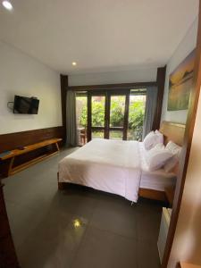 a bedroom with a large bed and a window at Rama Village in Canggu