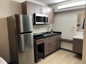 uma cozinha com um frigorífico de aço inoxidável e um micro-ondas em Westport Inn em Grande Prairie
