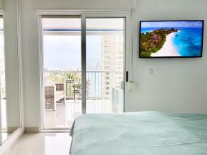 a bedroom with a flat screen tv hanging on a wall at La Perla Benidorm Apartment seaview & pool Levante Beach in Benidorm