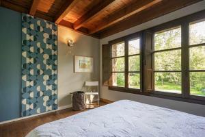 a bedroom with a large bed and windows at Casa escondida cuencu in Margolles
