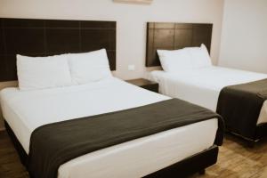 2 camas en una habitación con blanco y negro en Hotel Capital Frontera en Monclova