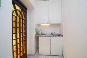 eine Küche mit weißen Schränken und einem Fenster in der Unterkunft Villa Glencoe -suite 3 in Mali Lošinj