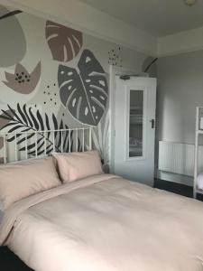 Un dormitorio con una cama blanca con hojas en la pared en The St. Leonards Guest House, en Shanklin