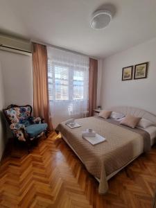 una camera con un grande letto e una sedia di R&S Apartments a Herceg-Novi
