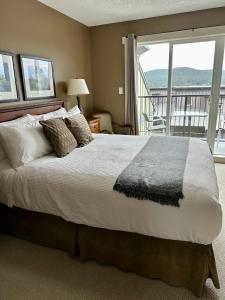 a bedroom with a large bed with a balcony at Race Rocks Townhouse - Sooke in Sooke