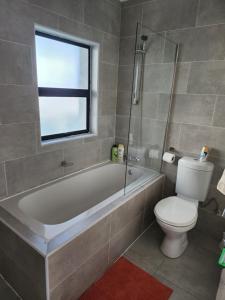 a bathroom with a tub and a toilet and a window at Sarona Studio A103 in Gaborone