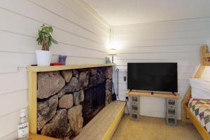 a room with a tv and a stone wall at Slope-Walk Condo in Sandpoint