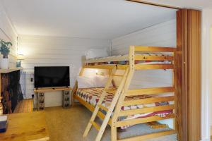 a bedroom with two bunk beds and a television at Slope-Walk Condo in Sandpoint