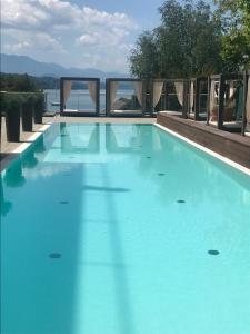 a large blue swimming pool with a view of the water at Apartment Lake`s in Pörtschach am Wörthersee