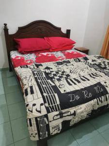 a bed with a black and white quilt and a red pillow at Teratak Tuan Muda Homestay in Melaka