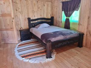 Bett in einem Zimmer mit einer Holzwand in der Unterkunft Cabaña El Angel in Alaska