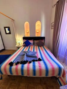 a bed with a colorful striped comforter in a room at Les Terrasses d'Essaouira in Essaouira