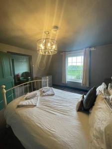 - une chambre avec un grand lit blanc et un lustre dans l'établissement Cosy Farm house in Forest of Dean, à Westbury on Severn