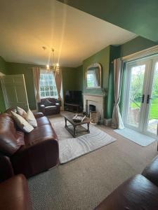 a living room with a leather couch and a fireplace at Cosy Farm house in Forest of Dean in Westbury on Severn