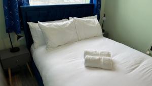 un letto bianco con cuscini bianchi e 2 asciugamani di Homestay in Walsall a Walsall