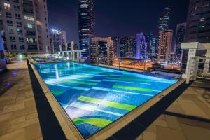 a swimming pool on top of a city at night at Marina Byblos Hotel in Dubai