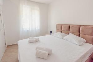 a bedroom with a large white bed with two towels on it at Apartman Smokva in Kumbor