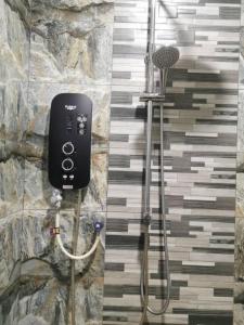 a shower in a bathroom with a stone wall at Teratak Tuan Muda Homestay in Melaka