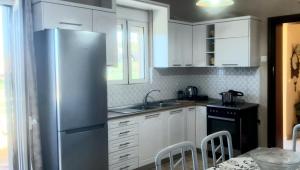 a kitchen with white cabinets and a stainless steel refrigerator at MARIA cozy apartments in Pigianos Kampos