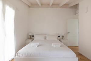 a white bedroom with a white bed with two pillows at Olmo Suites in Como