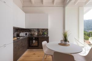 a white kitchen with a white table and chairs at Olmo Suites in Como