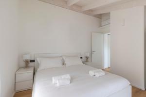 a white bedroom with a white bed with towels on it at Olmo Suites in Como