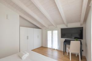 a white bedroom with a desk and a tv on the ceiling at Olmo Suites in Como