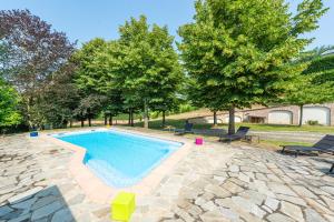 a swimming pool with chairs and trees in a yard at Villa Cornelia , entire Villa with private pool in Corneliano d'Alba