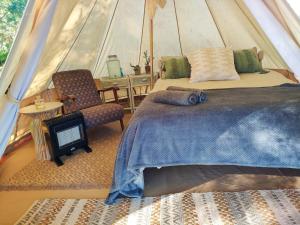 a bedroom with a bed and a chair in a tent at Gaia Double bell tent in Swellendam