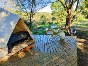 ein Zelt auf einer Holzterrasse mit einem Tisch in der Unterkunft Gaia Double bell tent in Swellendam