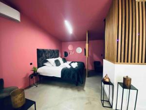 um quarto com uma cama numa parede cor-de-rosa em La Litchi Le 50 Suites and Spa centre ville em Bordéus