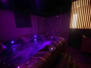 Habitación oscura con bañera con luces moradas. en La Litchi Le 50 Suites and Spa centre ville, en Burdeos