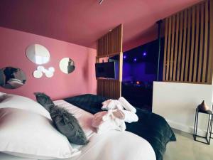 um quarto com 2 camas e uma parede rosa em La Litchi Le 50 Suites and Spa centre ville em Bordéus