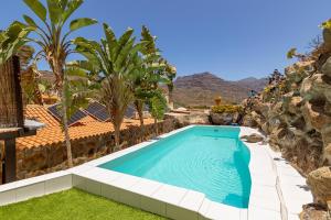 a swimming pool in a backyard with palm trees and a house at Casa Los Pinos in Mogán