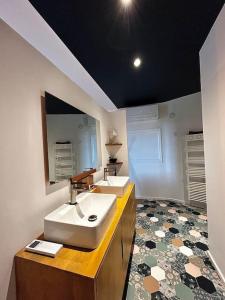 a bathroom with two sinks and a large mirror at La suite avec jacuzzi in Saint-Martin-de-Londres