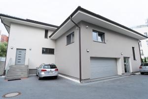 a white house with a car parked in a parking lot at The Dante Villa Apartments in Prague