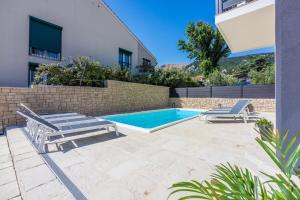 una piscina con 2 tumbonas junto a una casa en Villa BAŠKA near the beach, en Baška
