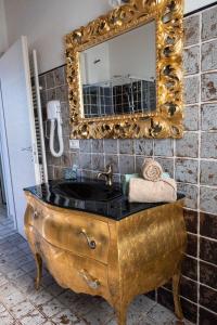 un lavandino dorato in bagno con specchio di Delta House a Taglio di Po
