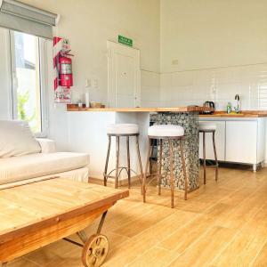 ein Wohnzimmer mit einer Küche mit einer Theke und Stühlen in der Unterkunft Moderno y tranquilo departamento in El Calafate
